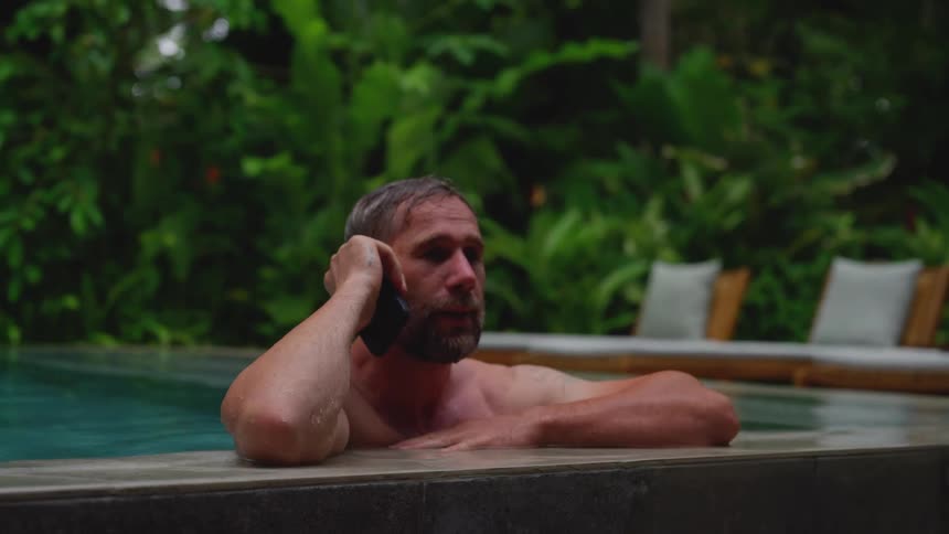 The man is talking on his phone in the pool