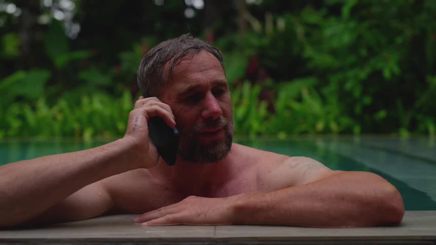 Man standing in a pool answers his cell phone and talks