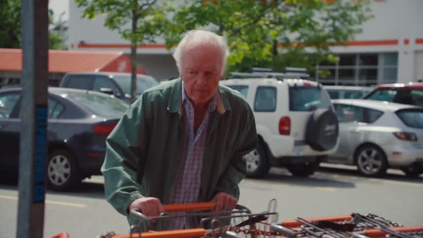The man slams his shopping cart in the corral and is very angry
