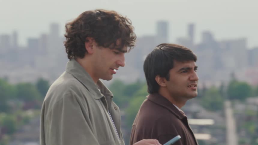 Two young men on the outskirts of town meeting another man who is on his smartphone at midday