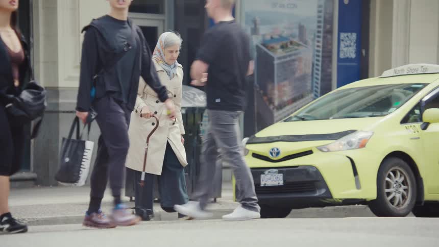 Elderly woman with a cane crossing the crosswalk with other people