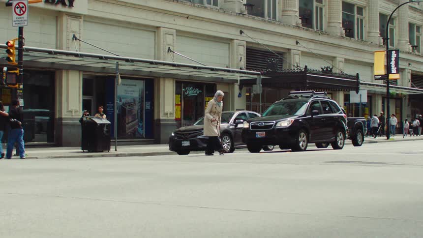 Elderly woman crossing a street with other people