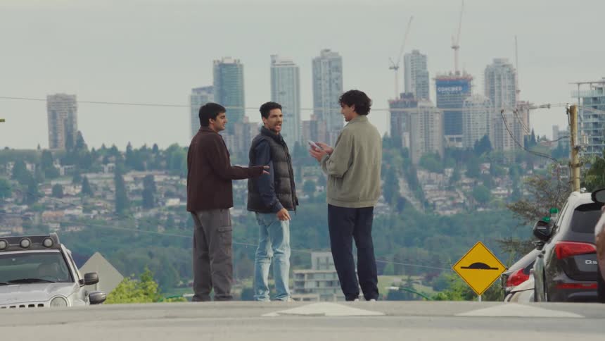 Three men stop in the road to check a cell phone