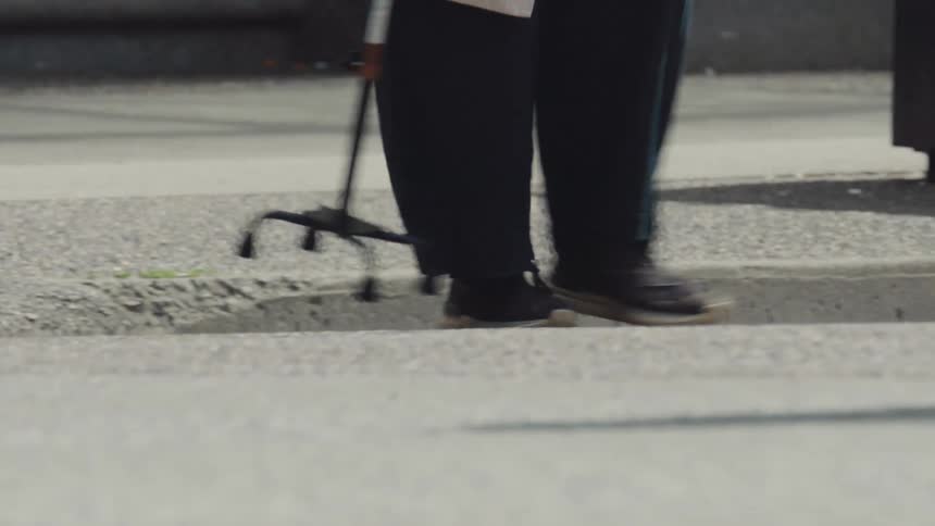 A woman uses a cane to cross the road