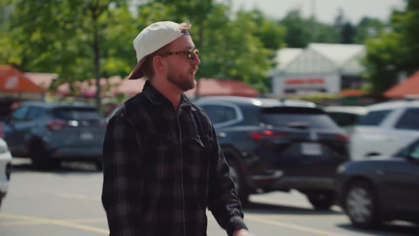 Man in cap and glasses in parking lot talking excitedly
