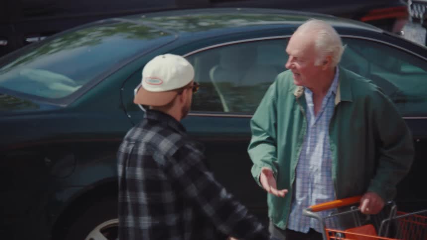 Elderly man arguing with another young man with shopping cart in parking lot