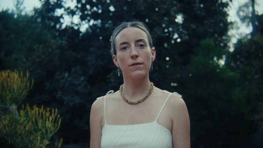 Blonde woman with her hair tied up in a backyard with trees