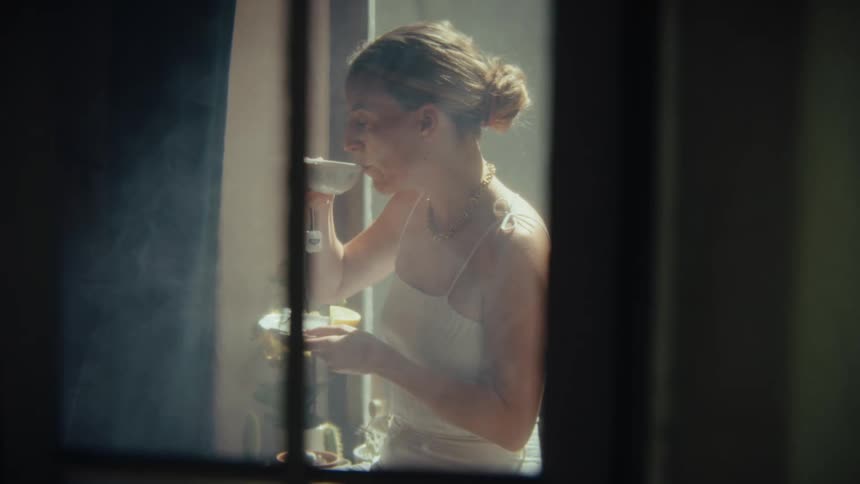 A young woman drinking a cup of tea indoors