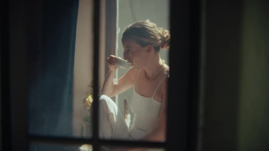 Woman in white dress sitting drinking tea from a mug