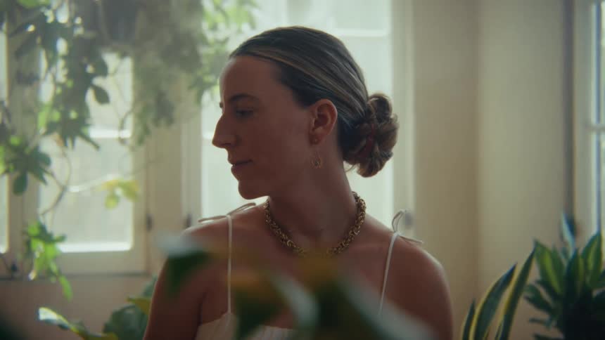 Woman with her hair tied up in an indoor area with green plants