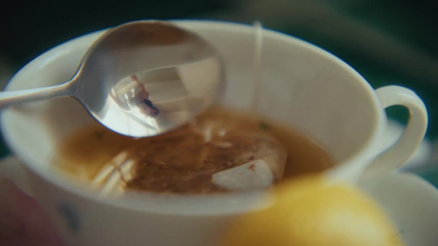 A spoon placed in a cup of tea containing tea residue