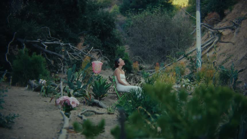 A woman sitting on a chair outdoors in a forest area during daytime
