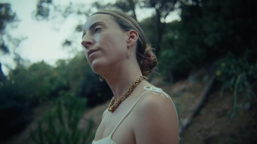 Woman outdoors with trees around and hair tied up