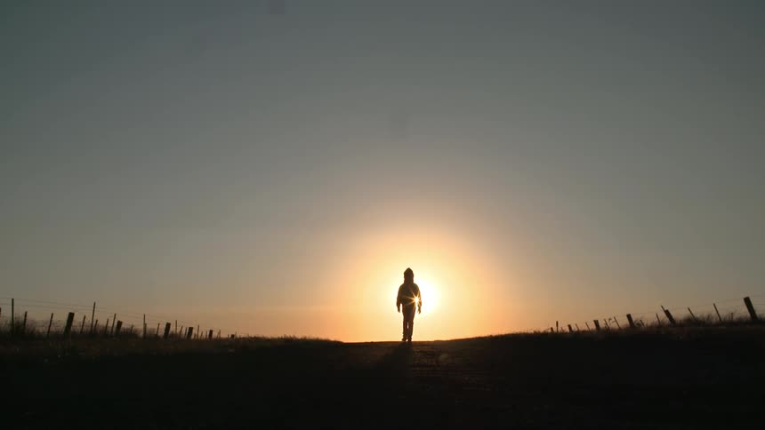 Silhouette of child walk towards a sunset
