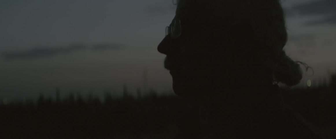 A man stands outdoors at dusk