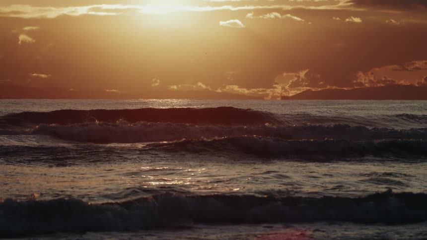 The sky is red as the sun rises on the beach