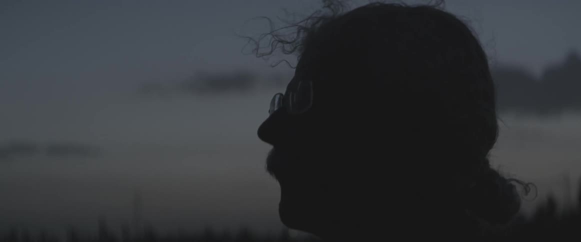 A man stands outdoors at dusk