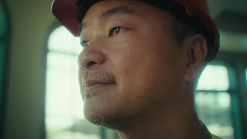 Man with a safety helmet indoors typing on a tablet