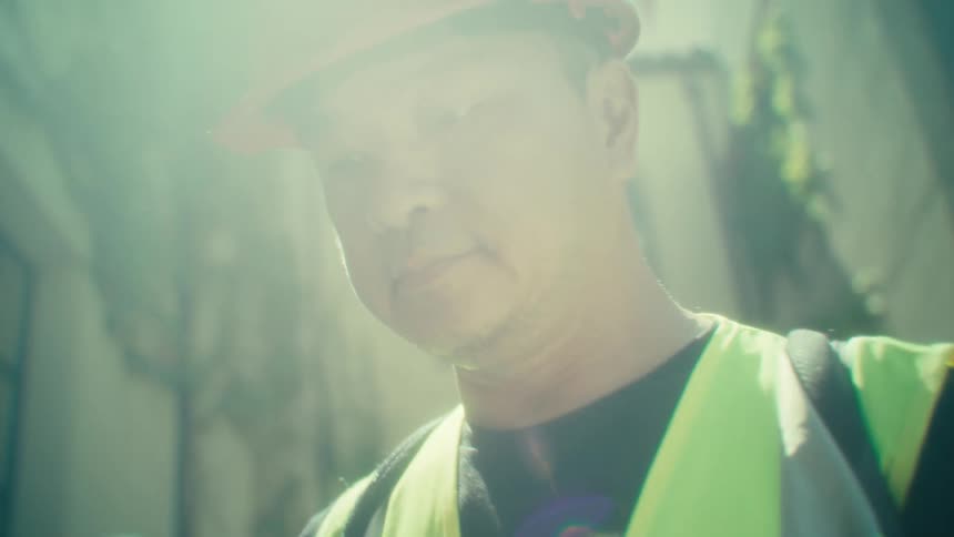 Man wearing a hard hat outdoors interacting with an ipad
