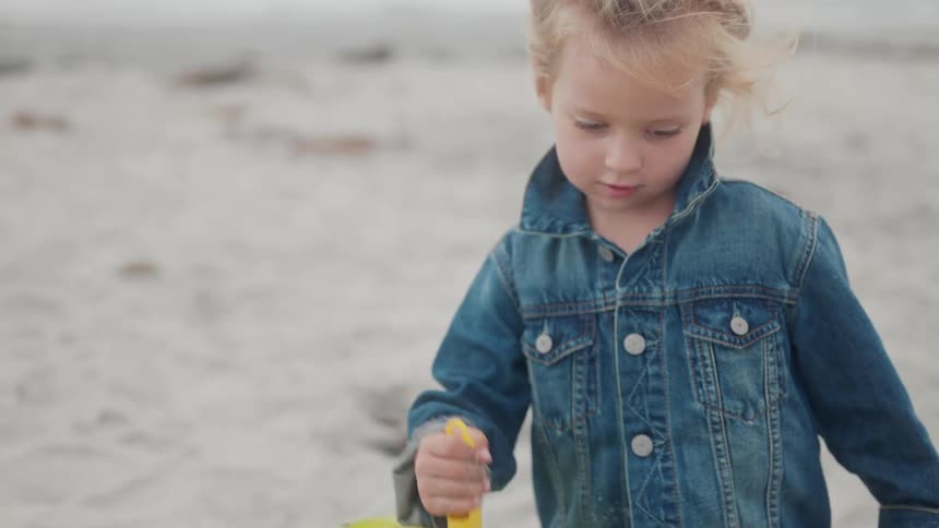The girl digs in sand on the beach