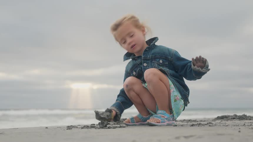 Young girl scooping sand with a shovel at the beach