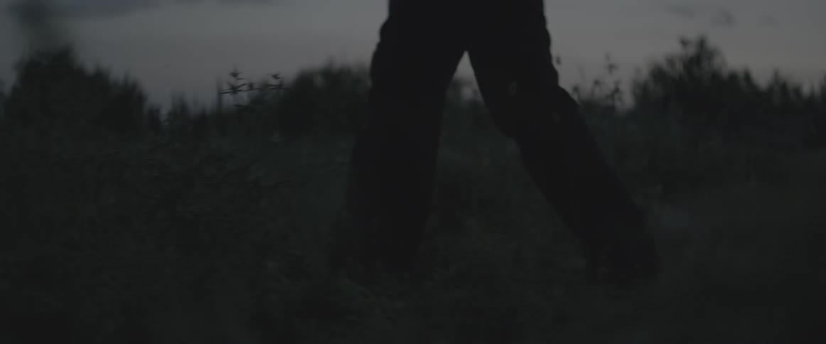 A man is hiking over a field at dawn