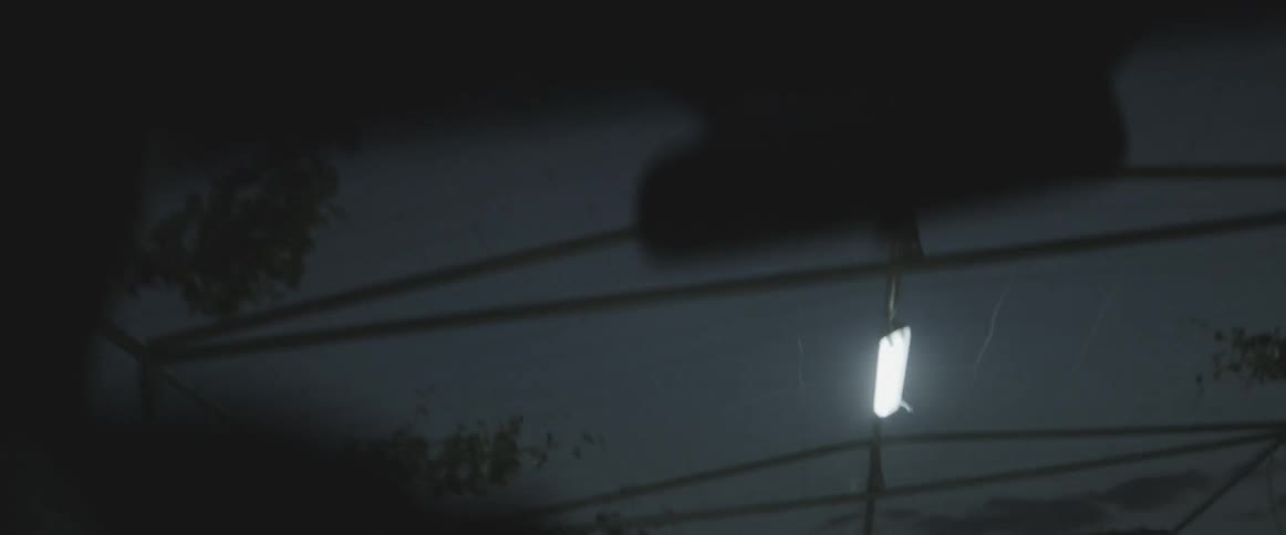 A vehicle drives beneath a covering with fluorescent lights at night