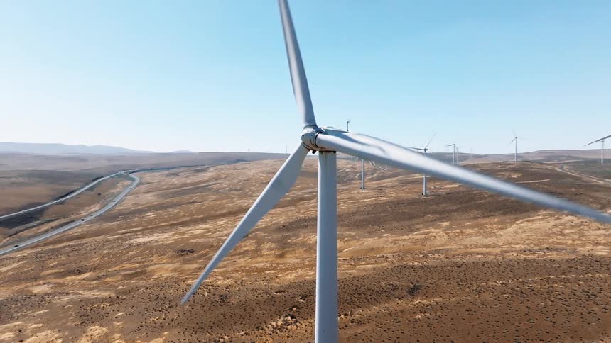 A wind turbine farm with the turbines spinning clockwise at midday