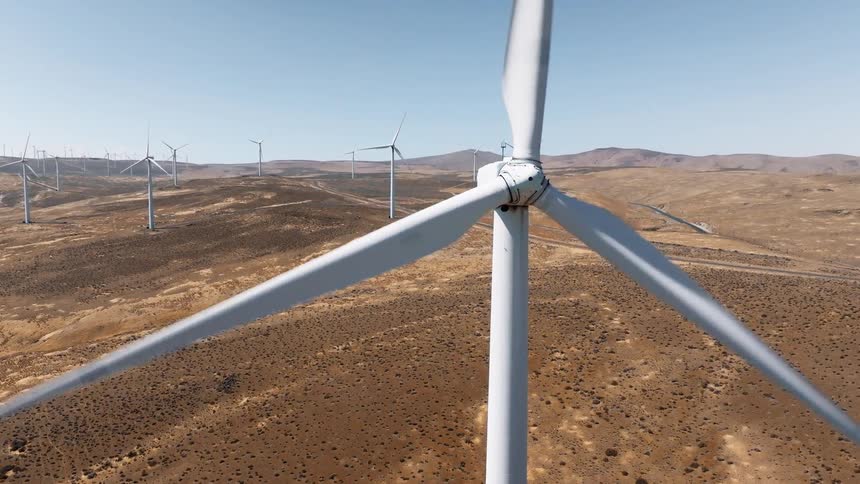 Wind turbines in a vast field with mountains in the background