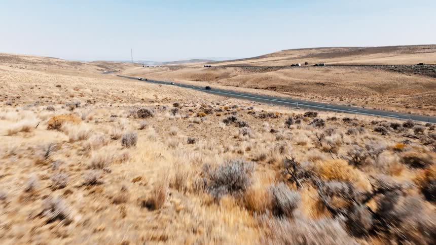 A freeway running through a badland with a series of cars passing by at midday