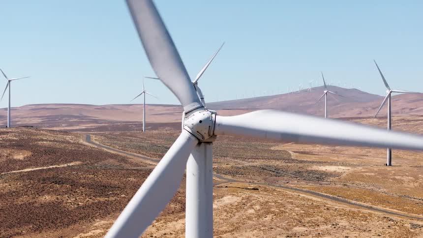 Wind turbines turning in sync in a wind farm near the mountains