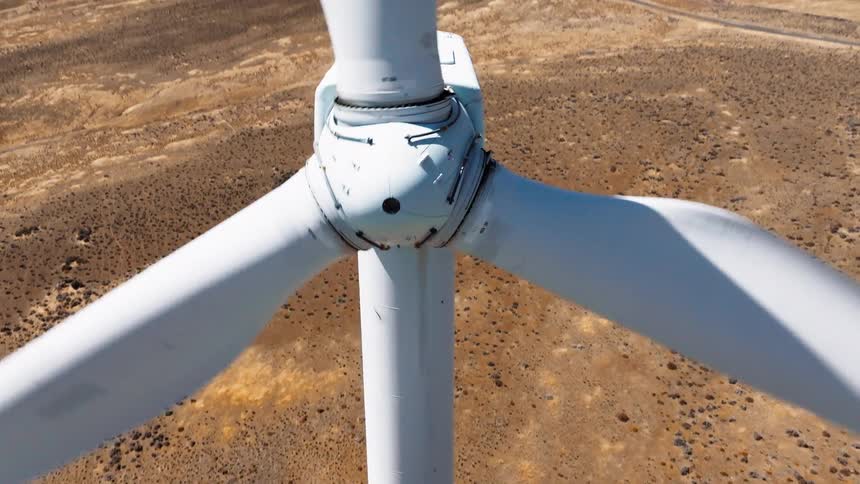 Wind turbines turning along a road leading to the mountains