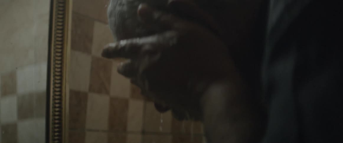 A man washes his face at a bathroom sink