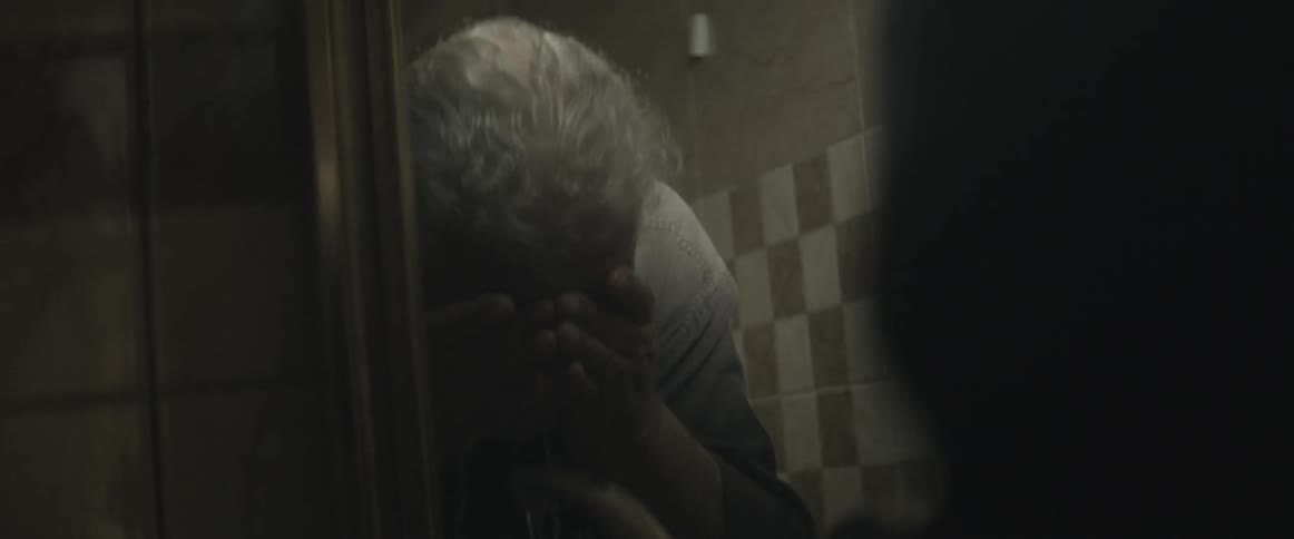 A man washes his face at a bathroom sink