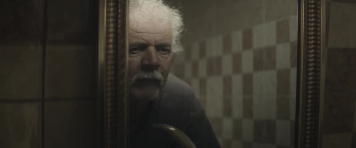 An older man looks into a mirror