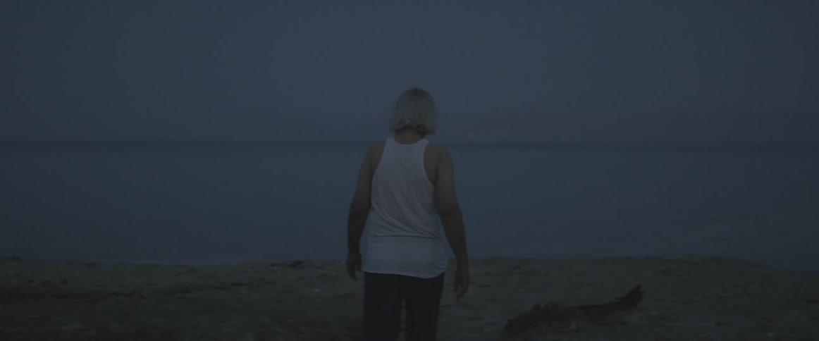 An elderly man walks towards the water on a beach