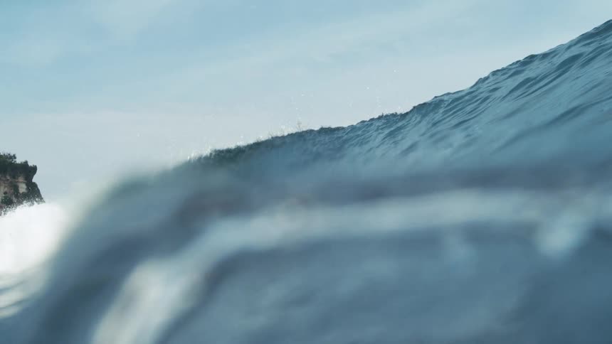 Ocean wave cresting under a clear blue sky capturing the smooth curve and calm motion of the water
