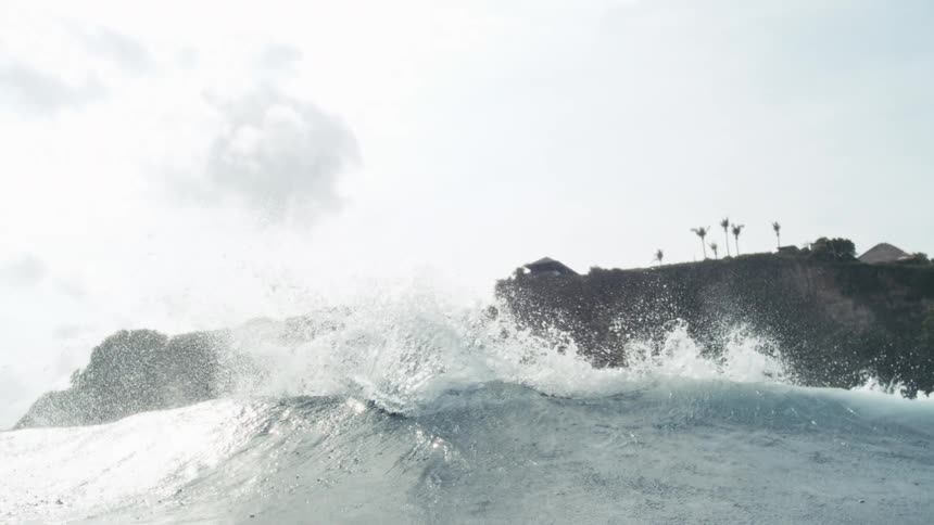 A surfer swimming in the ocean near the shore preparing to ride the waves forming at midday