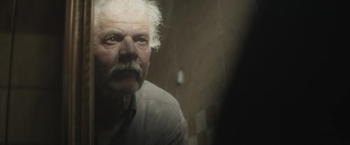 An old man looks up and stares at his reflection