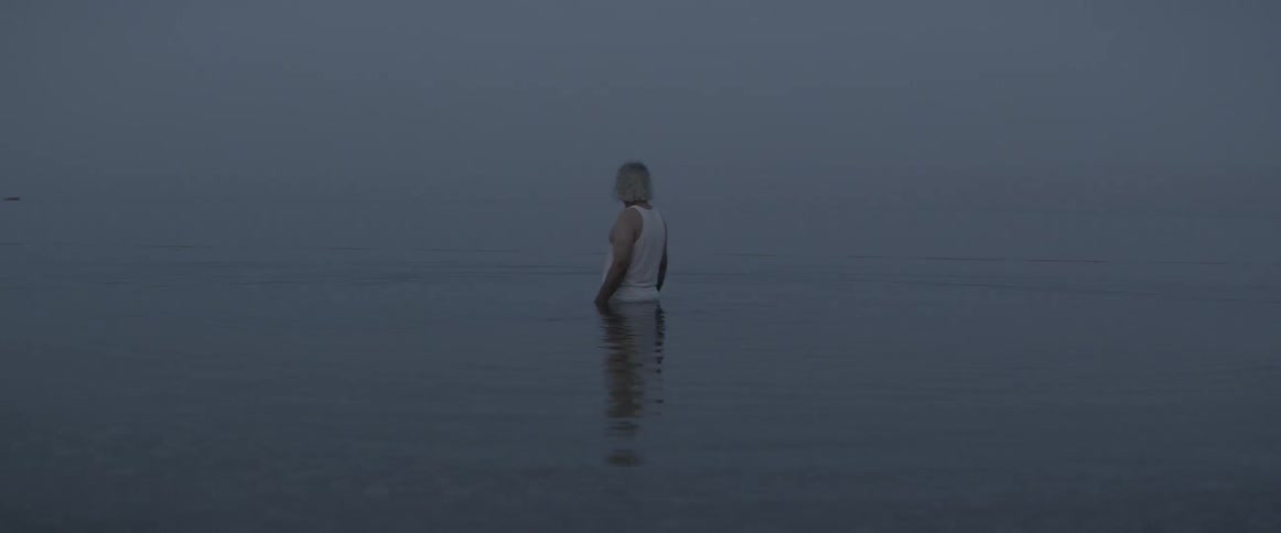 A man is standing waist deep in the water