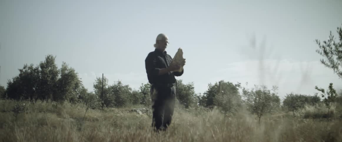 A man lifts a stone on a field