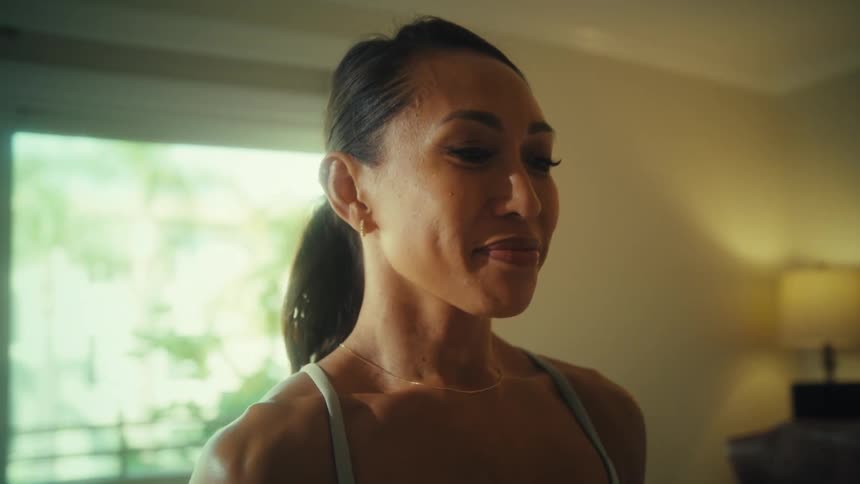 A young woman doing indoor exercise lifting dumbbells with a smile on her face