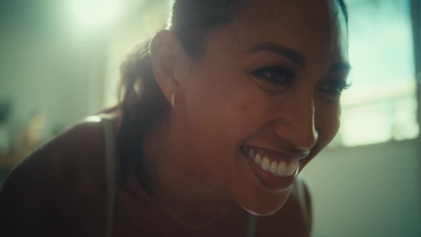 A smiling woman leans forward in warm indoor light