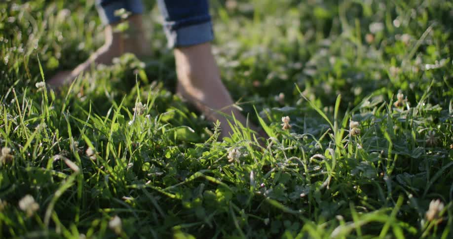 Close up of a womans feet as she stands and walks on a grass field outdoors during daytime
