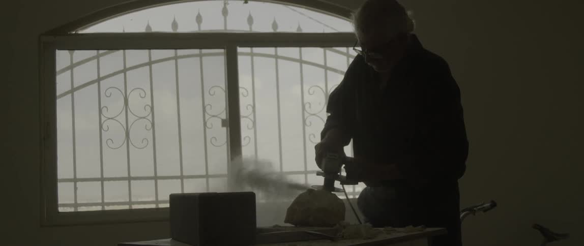 A man uses a power tool to grind down a rock