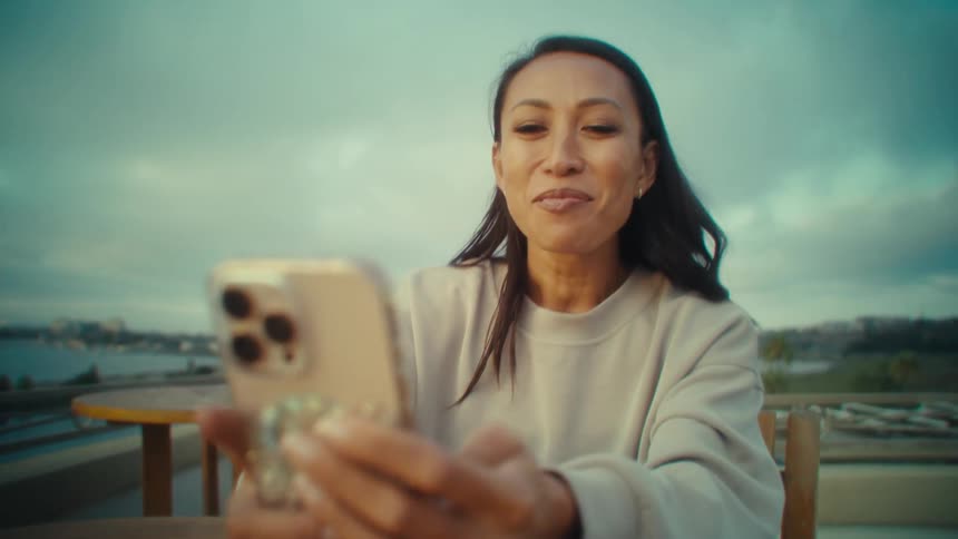 Woman sitting with a happy expression and interacting with a smartphone