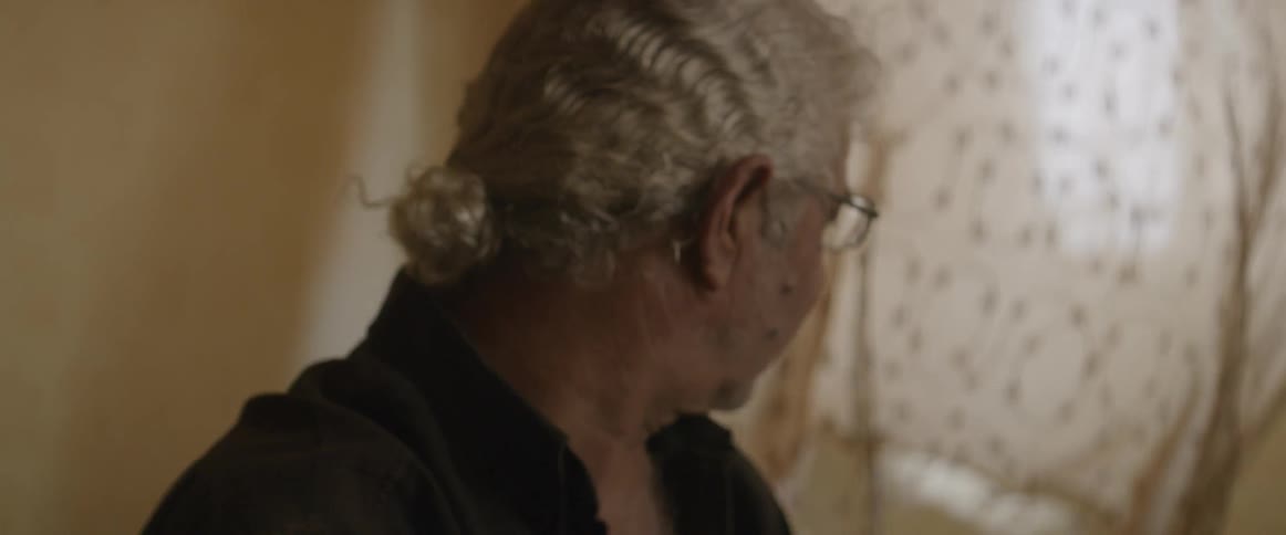A man looks over to a blowing curtain