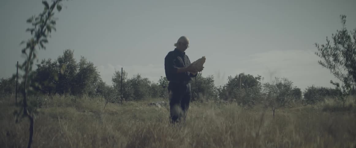 A man holds a sculpture outdoors