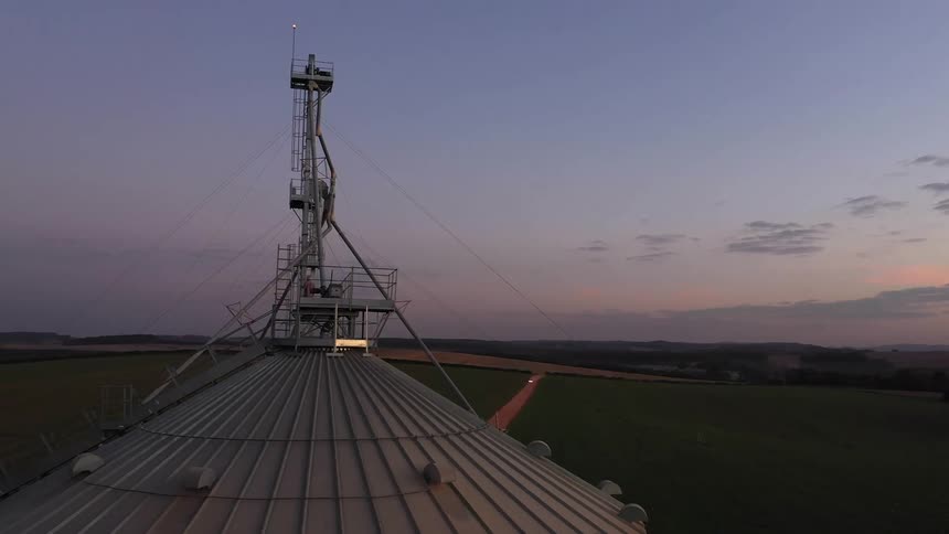 A vast agricultural landscape at dawn or dusk dominated by a towering grain silo