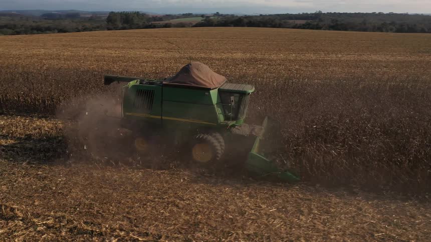 A combine harvester collects crops in a large farmland during daylight